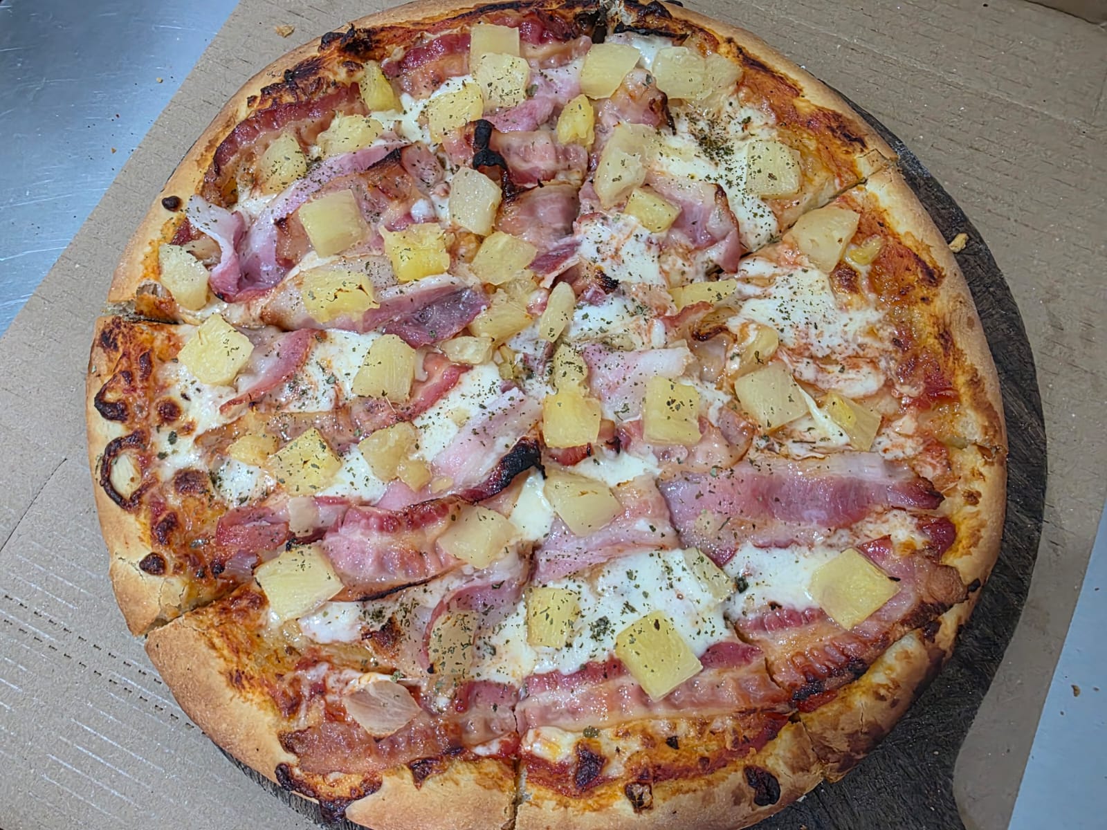 Pizza de Pizza Sur con bacon y trozos de piña recién horneada
